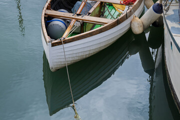 wooden boat moored with reflections on the water, close up.
