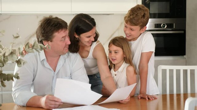 Happy satisfied family reading documents together while sitting at the table at home. High quality 4k footage
