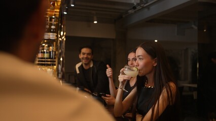 Friends talking while waiting Margarita cocktail savoring sour tasty drink drinking with couple at luxurious counter bar creating happiness moment meeting Friday night at vibrant nightclub. Vinosity.
