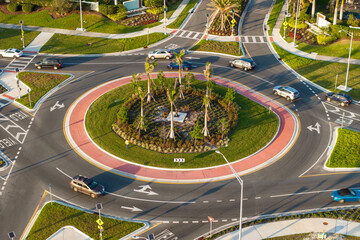 Roundabout crossroads on American city street with moving traffic cars. Circular transportation...