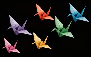 Obraz premium Colorful origami paper cranes arranged in a dynamic pattern against a black background