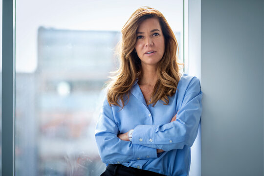 Confident middle aged business woman standing in a modern office overlooking the city