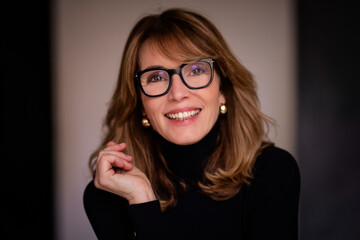Woman in her late 50's with blond hair inside smiling portrait