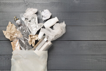 Bag with unsorted waste on wooden background, top view