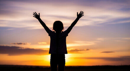Fototapeta premium Silhouette of girl with arms raised at sunset enjoying freedom and happiness