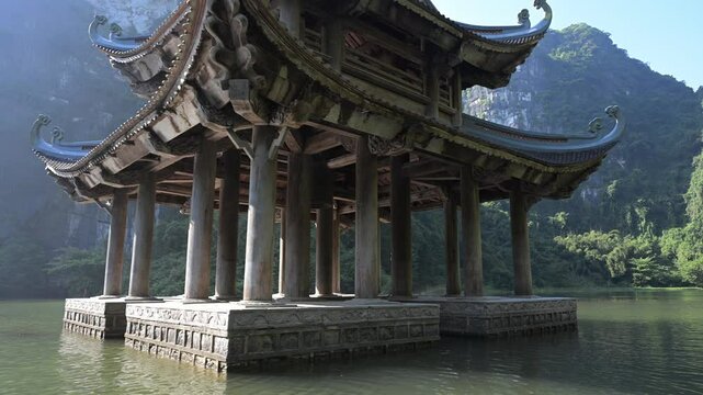 Traditional vietnamese temple standing on water with karst mountains in background in Ninh Binh province