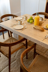 Petit déjeuner appétissant servi sur une élégante table en bois avec chaises en cannage, dans...