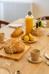 Petit déjeuner appétissant servi sur une élégante table en bois avec chaises en cannage, dans une salle lumineuse et chaleureuse.