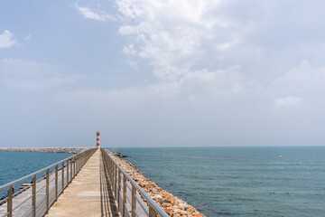 Obraz premium Pier leading to red and white lighthouse in Port-la Nouvelle, France