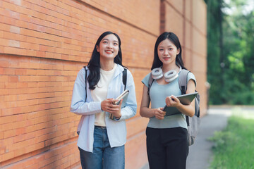 Naklejka premium Two Asian Female Students Walking on Campus