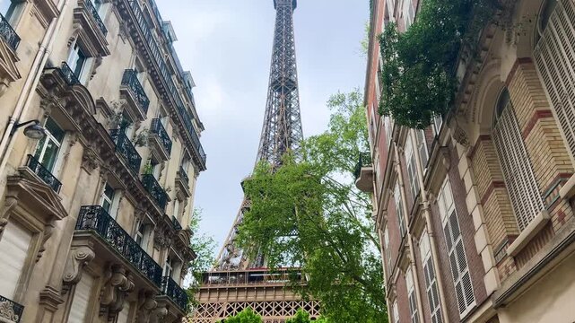 View of beautiful historic buildings and the Eiffel Tower from lively Rue Buenos-Ayres street, 8th arrondissement, Paris, France.