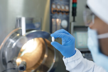 Pharmaceutical Worker Inspects Pill for Quality Control in Modern Medicine Manufacturing Facility