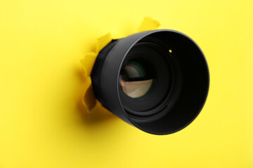 Hidden camera lens through hole in yellow paper, closeup