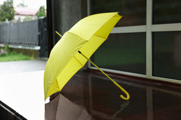 One yellow umbrella on wet asphalt outdoors