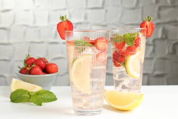 Tasty refreshing drink with strawberries, lemon and mint on white table, closeup