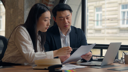 Two business managers coworkers Asian colleagues work together teamwork documents analyze Chinese woman girl female businesswoman Japanese Korean man male guy businessman talk cooperate management