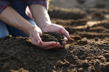 Man holding pile of soil in field, closeup