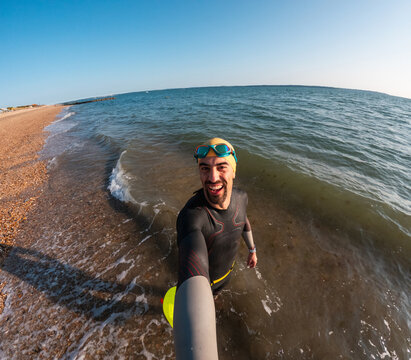 Triathlete taking selfie while training in open water on sunny day - Powered by Adobe