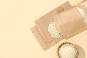 Zipper stand-up pouches with white rice on beige background, flat lay. Mockup for design