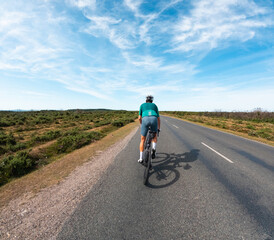 Cyclist riding road bike on asphalt road in scenic landscape