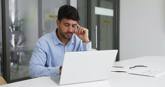 Thoughtful Hispanic businessman managing emails, working on project looks at laptop screen with serious or concerned expression, solving work-related issues, make decision, search solutions in office
