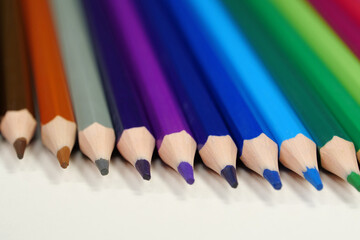 New wooden colored pencils of rainbow colors, perfectly sharpened, lie on table