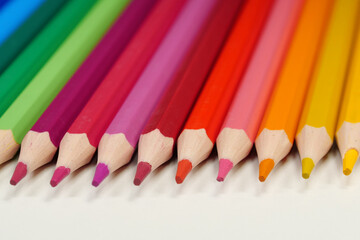 New wooden colored pencils of rainbow colors, perfectly sharpened, lie on table