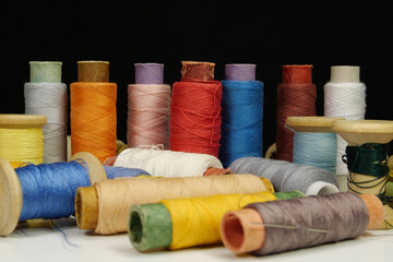 Spools with multi-colored threads on black background, close-up shot