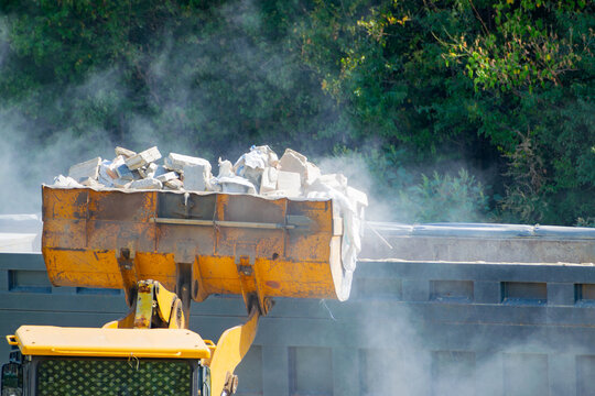 Removing construction waste with a bulldozer. loading into a dump truck - Powered by Adobe