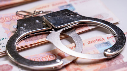 Handcuffs on five-thousandth banknotes: the concept of bribes, corruption, crime.