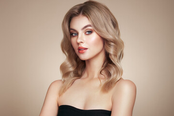 Fototapeta premium A beautiful young woman with shiny wavy blonde hair. Model with healthy skin, close up portrait. Cosmetology, beauty and spa