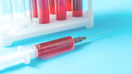 Syringe with a red liquid in it is on a blue background. The syringe is labeled with the number 2