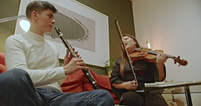 Two musicians, a clarinetist and violinist, harmonize beautifully in a cozy home setting.