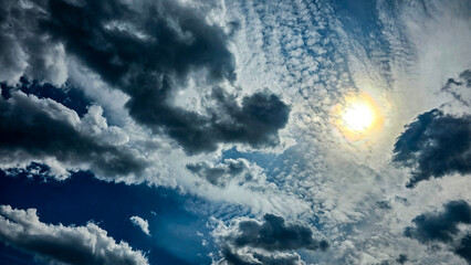 Dramatic cloudy sky with the sun shining through dense clouds. Moody weather background with...