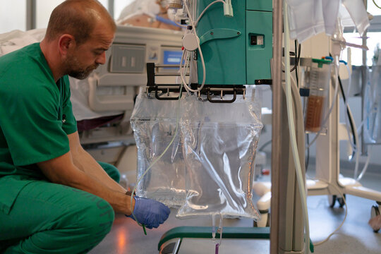 Doctor adjusting iv drip bags in hospital room with patient - Powered by Adobe