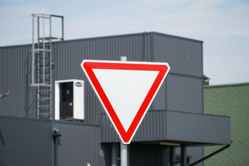 A traffic yield sign stands prominently in front of a contemporary structure, providing clear...