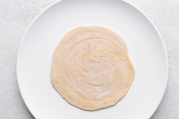 Overhead view of paratha dough rolled out, top view of flaky flatbread dough, process of making paratha