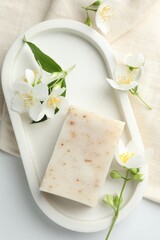 Soap bar and jasmine flowers on white table, flat lay