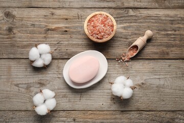 Soap bar, sea salt and cotton flowers on wooden table, flat lay