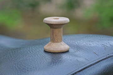 one old gray small wooden spool of thread stands on a black table on a summer street