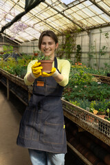 Young woman presents a freshly potted plant with care and precision.