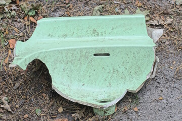 one dirty green piece of broken ceramic washbasin lies on the gray ground on the street