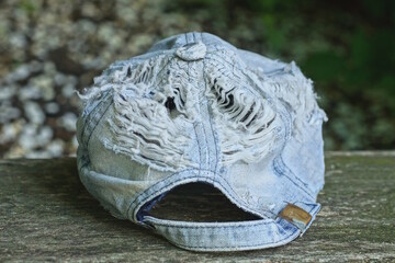 one old cotton torn blue white baseball cap with holes lies on a gray table on a summer street