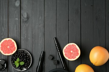 Hookah, coal and fresh fruits on black wooden table, flat lay. Space for text