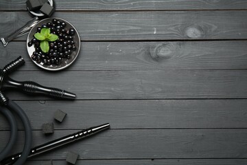 Hookah, coal, mint and currants on black wooden table, flat lay. Space for text