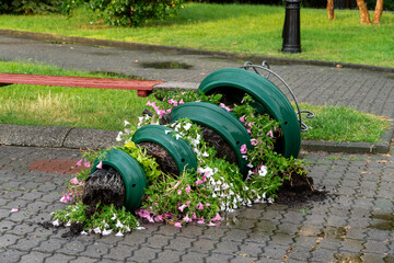 Colorful flower pots lie overturned on the sidewalk, spilling vibrant petunias and soil. Lush...