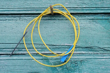 a skein of yellow wire hangs on a green wooden wall on a summer street