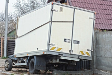 one large closed white trailer on wheels stands on a city street by the road