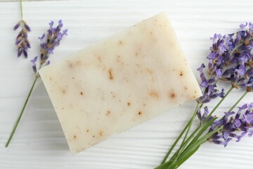 Soap bar and lavender flowers on white wooden table, flat lay