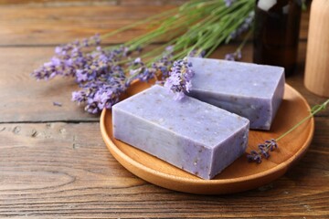Soap bars and lavender flowers on wooden table, closeup. Space for text